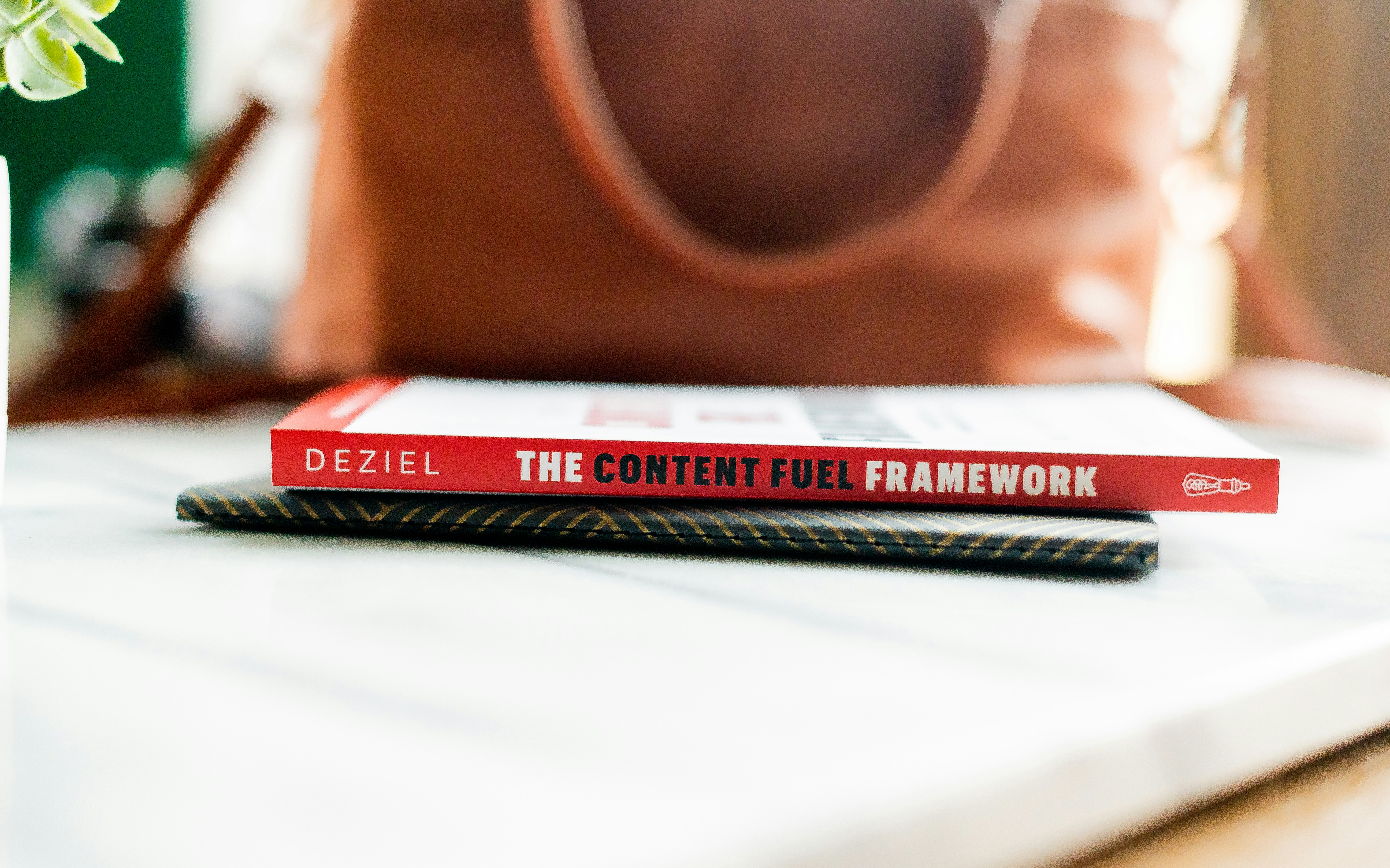 A book and a notebook stacked in front of a purse.