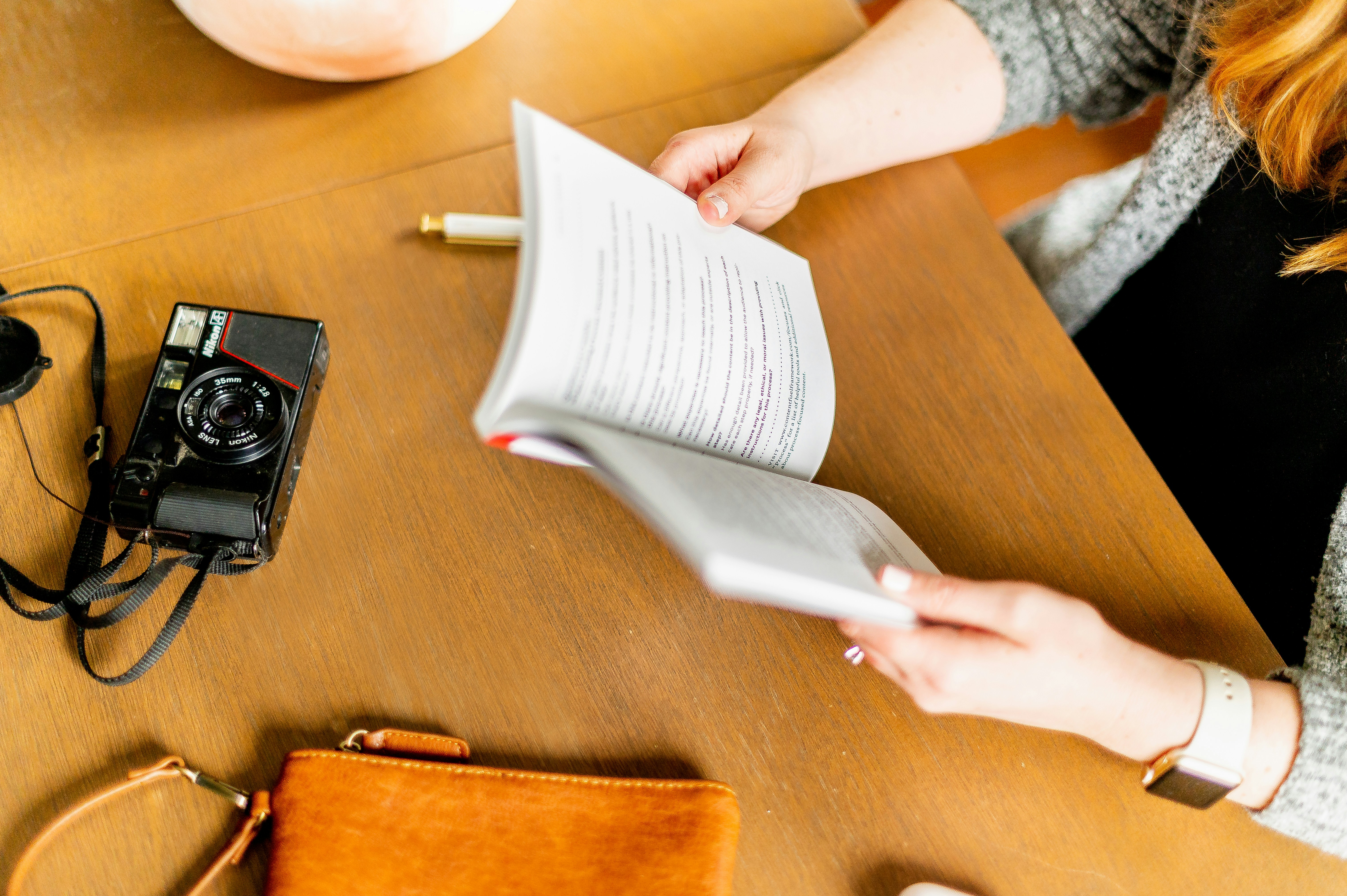 person holding white book page on brown wooden table