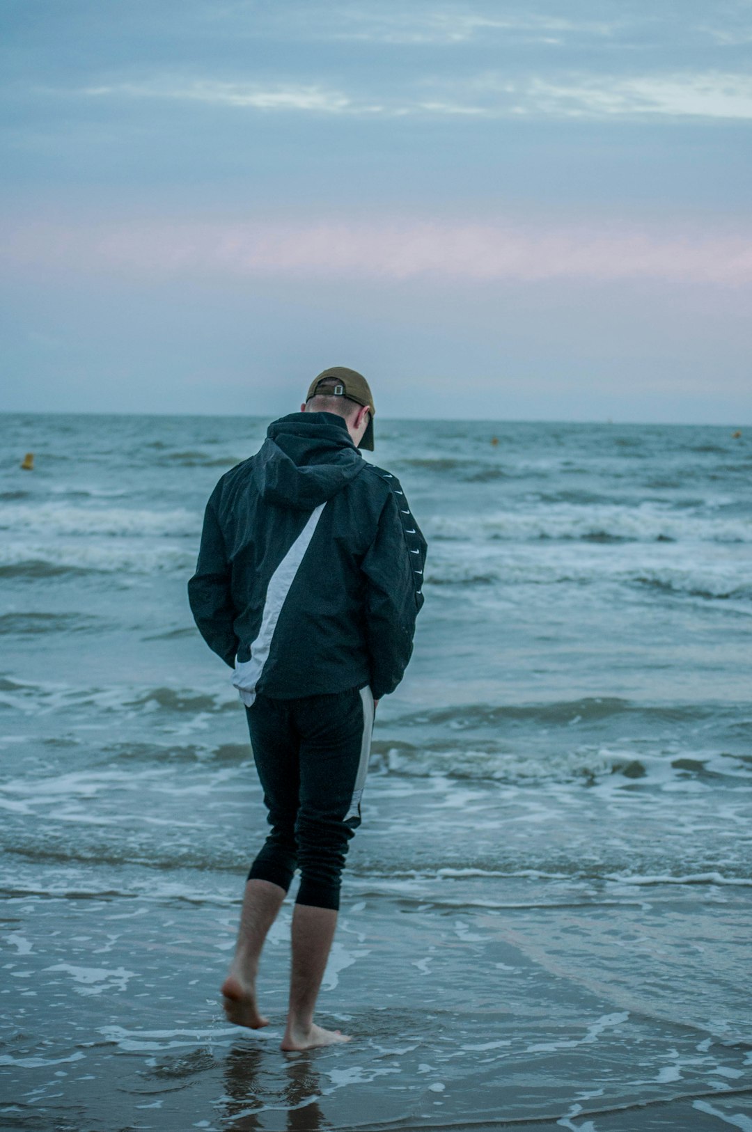 man in gray hoodie standing on sea shore during daytime