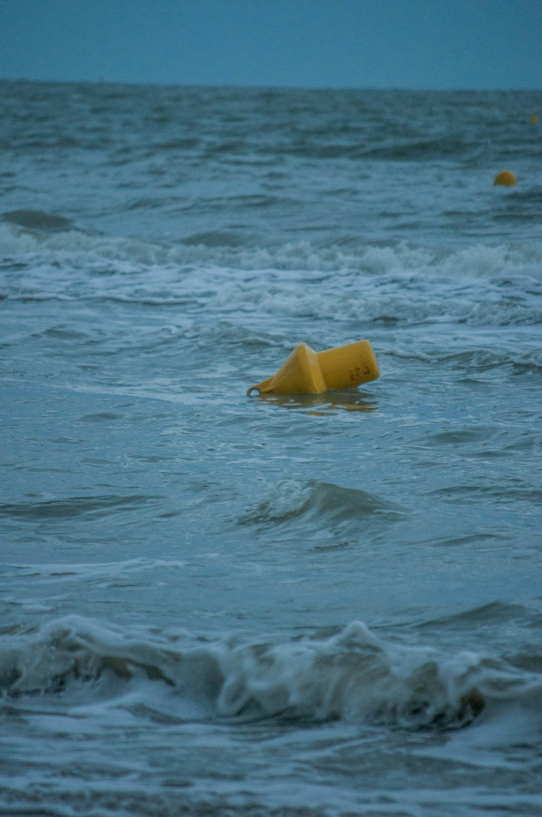 yellow plastic bucket on water during daytime