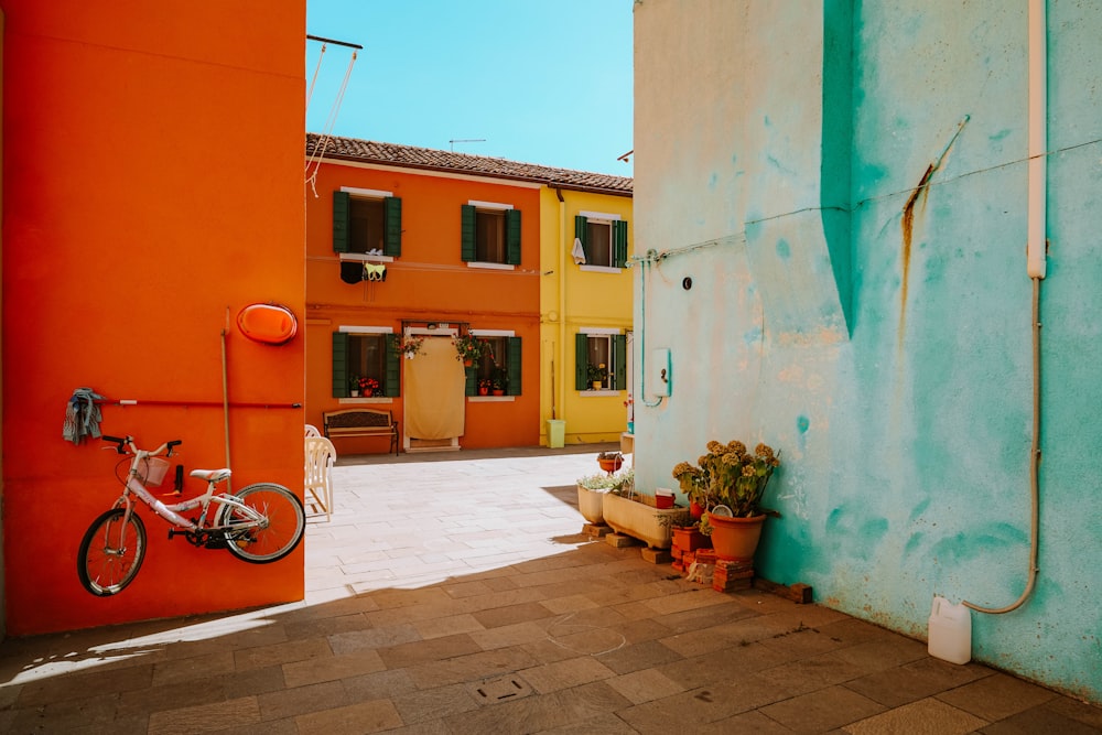 red bicycle parked beside green and brown concrete building during daytime