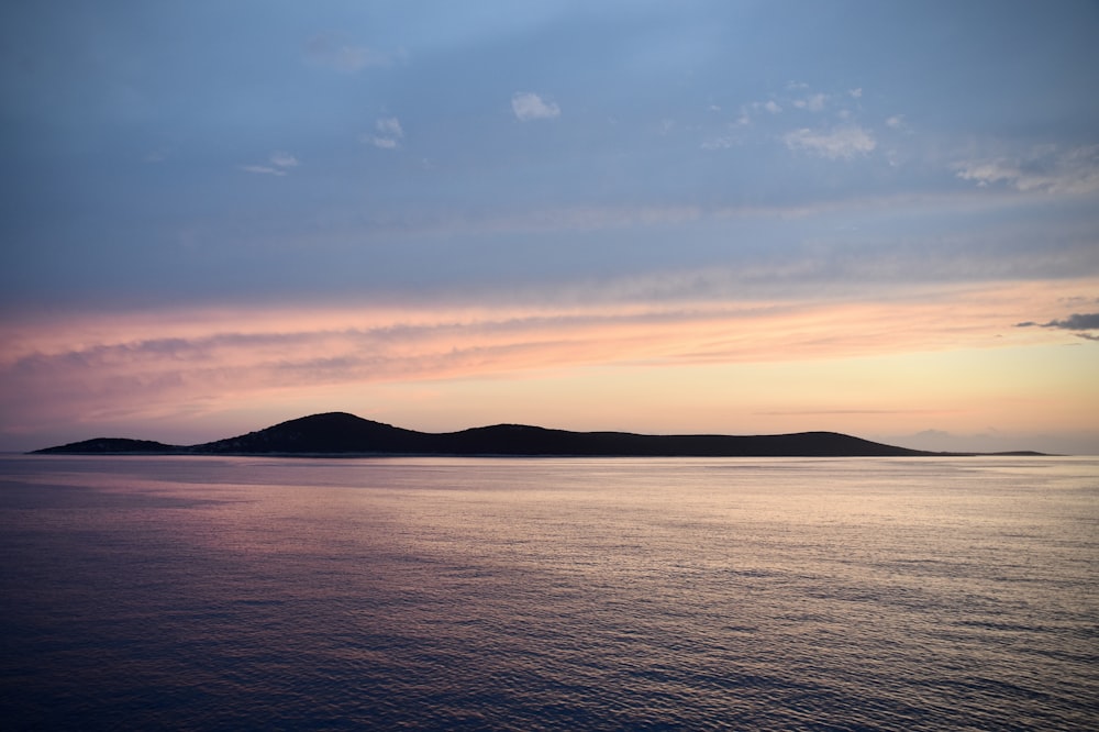 body of water near mountain during sunset