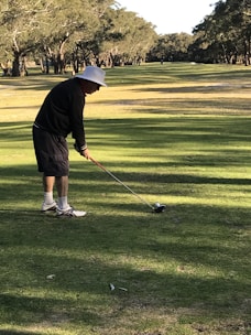 A golfer practicing swings with a training aid on a sunny driving range.