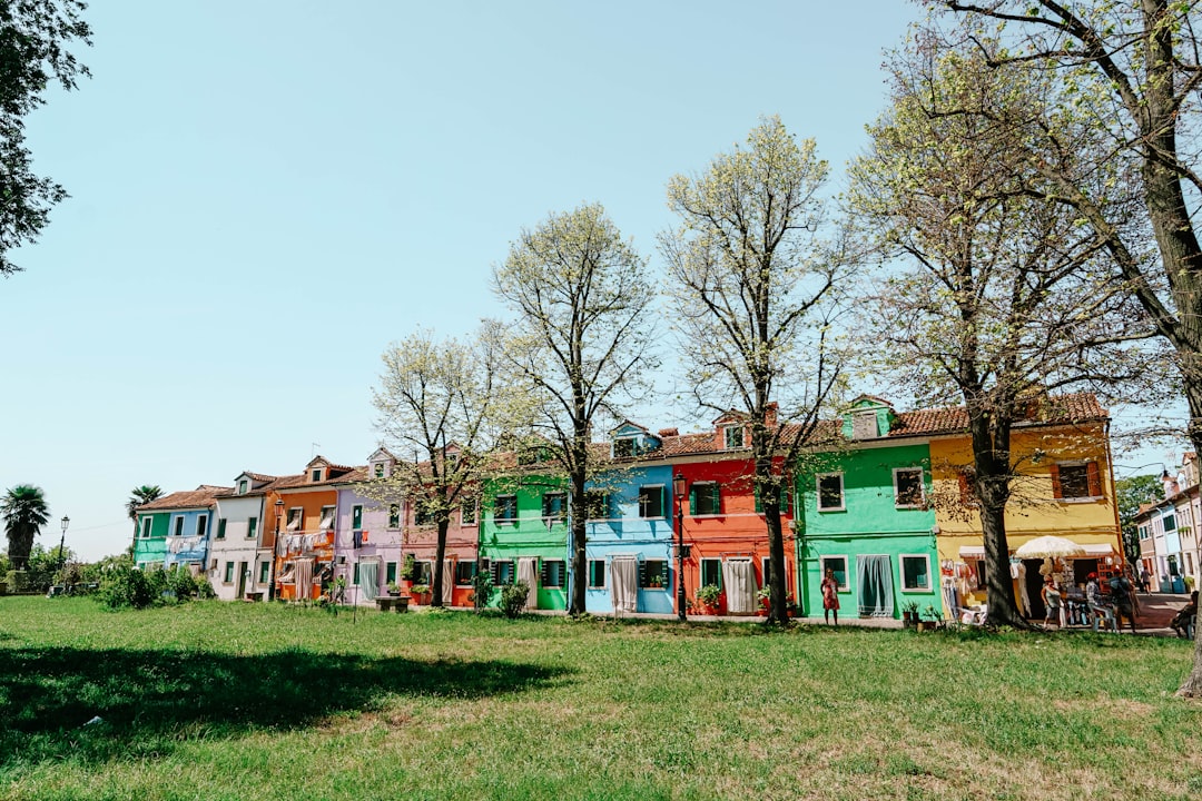 white and red concrete houses near green trees under white sky during daytime