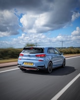 A beautiful Hyundai hatchback driving through picturesque scenery.