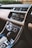 A modern car interior showcasing a sleek dashboard with a touchscreen infotainment system displaying media and phone options. There are various control dials for air conditioning and other functions, along with a gear shift lever in the foreground.