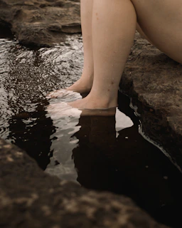 person in black shorts sitting on rock