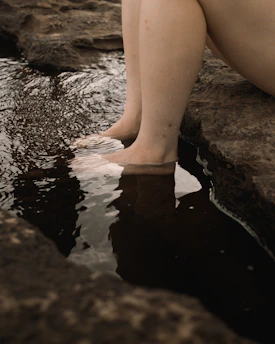 person in black shorts sitting on rock