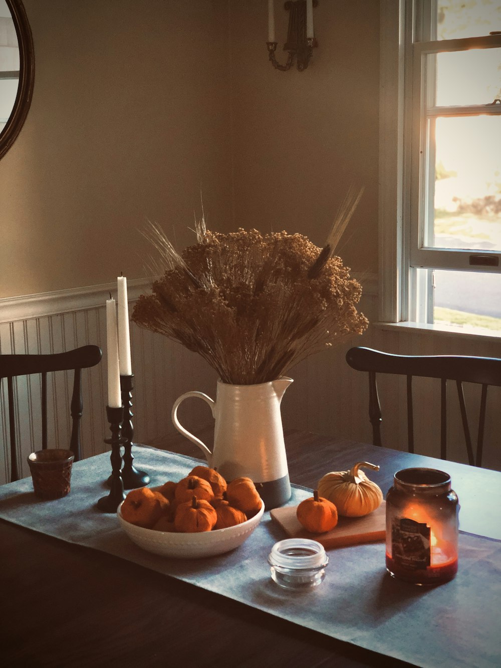 Jarrón de cerámica blanca con planta marrón sobre mesa de madera marrón