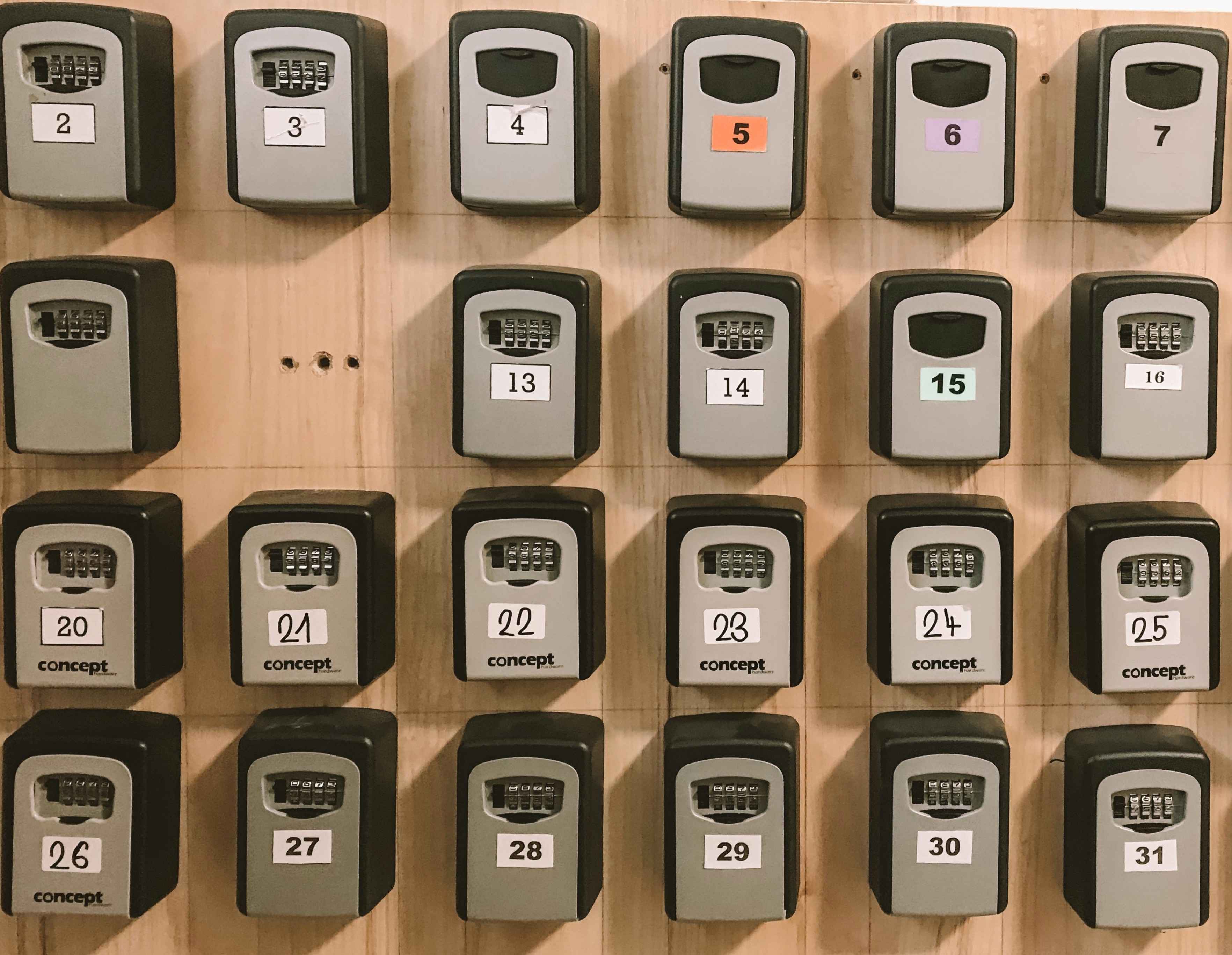 Grid of numbered key lockboxes mounted on a wooden wall, each individually coded