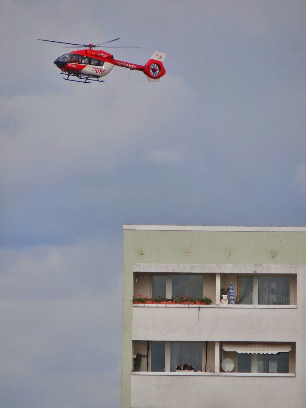 red and black helicopter flying over white building during daytime