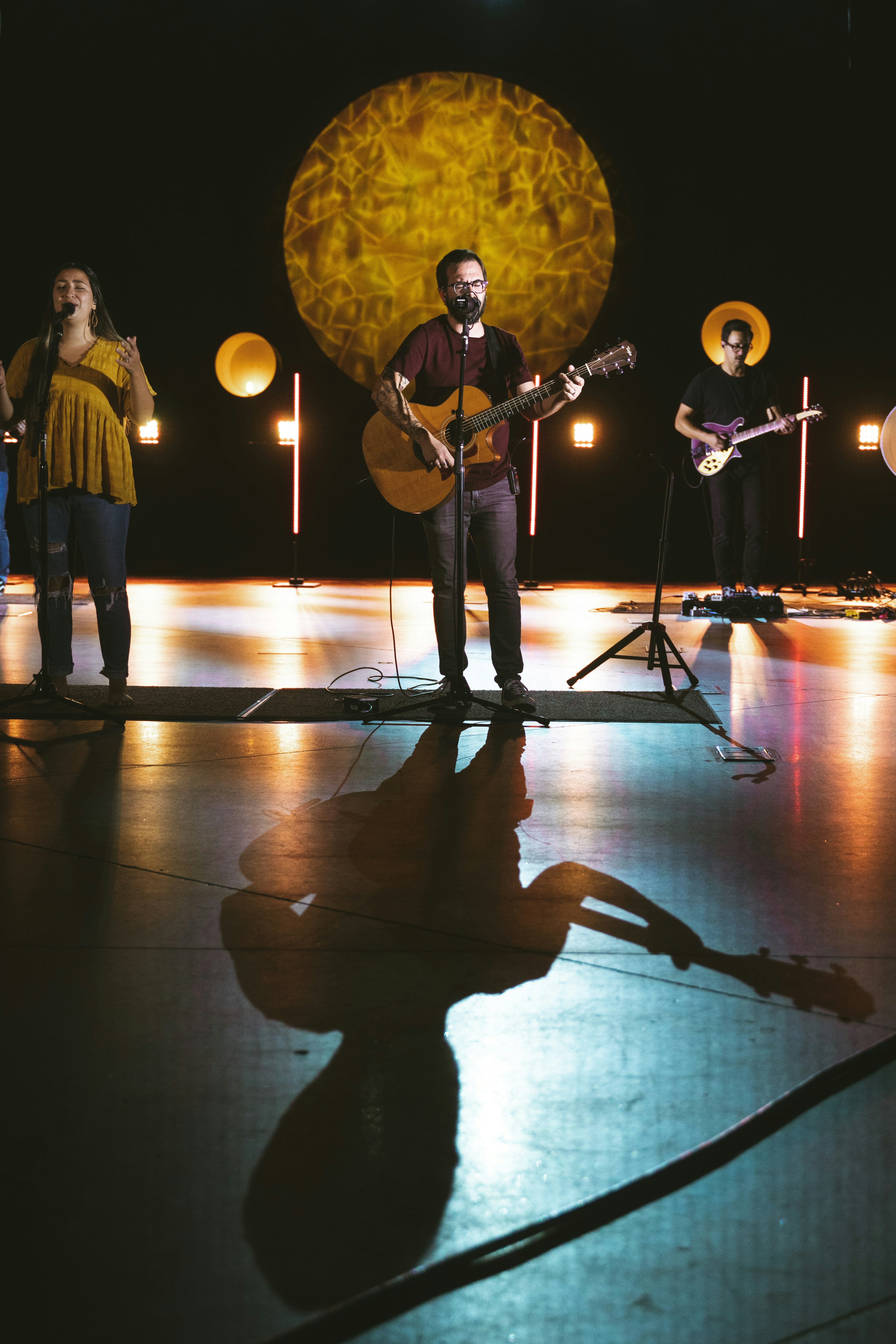 Bright concert stage with warm stage lighting, musician performing, vibrant colorful backdrop