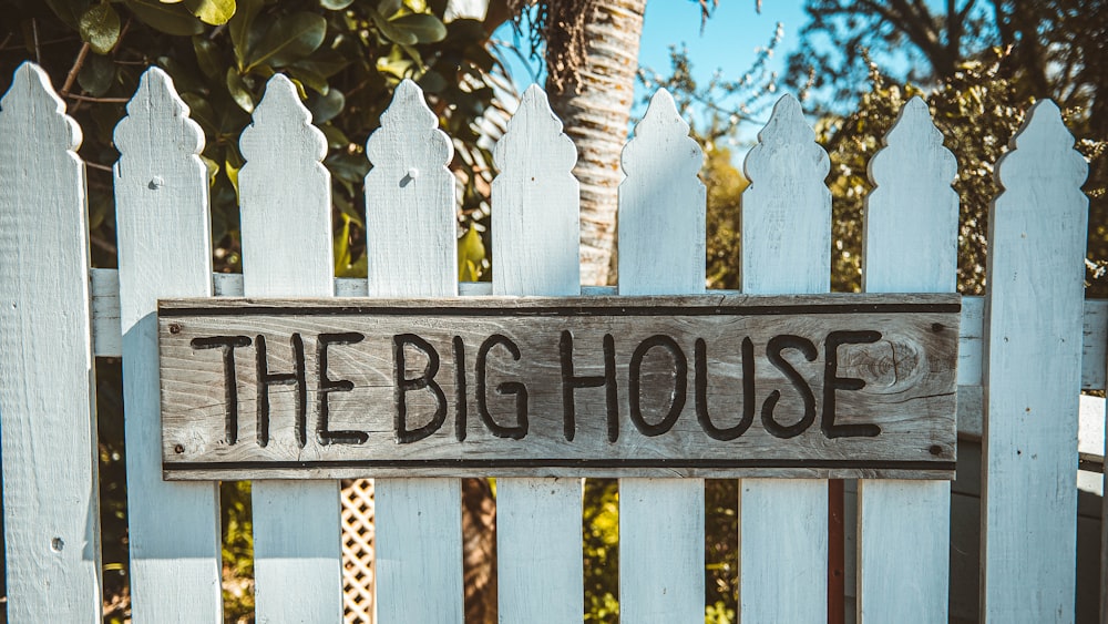 white wooden fence with black and white wooden signage