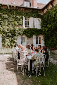 people sitting on white chairs near green trees during daytime