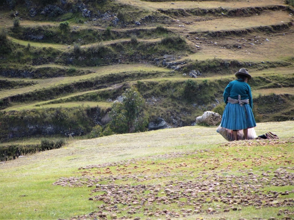 woman in blue dress walking on green grass field during daytime