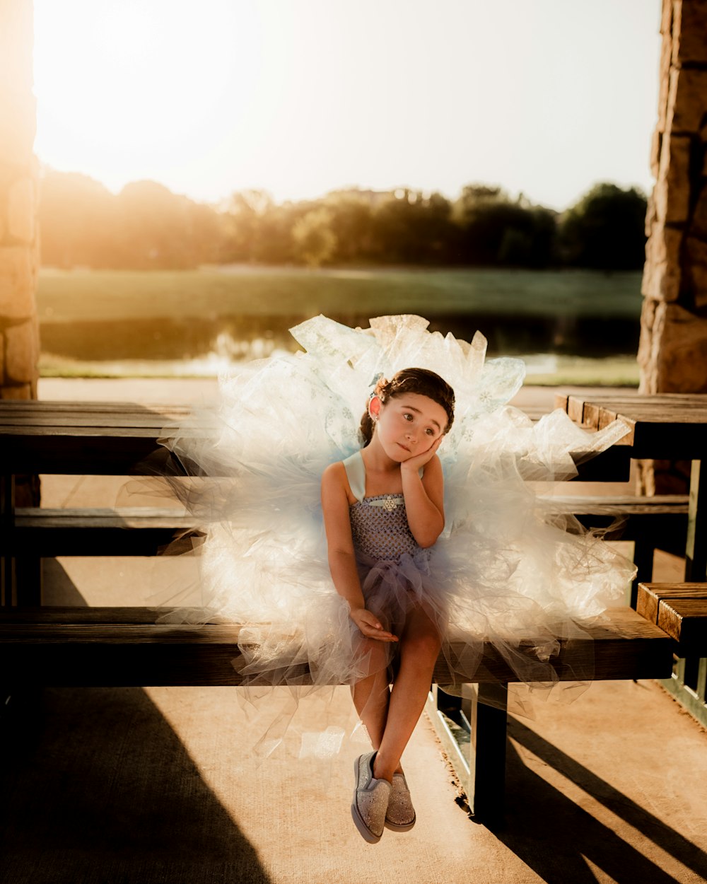 girl in white dress sitting on wooden bench