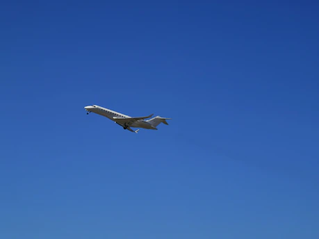 A luxurious private jet soaring through a clear blue sky.