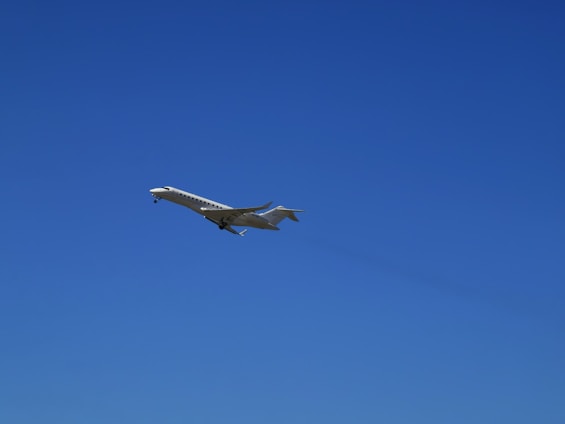 A sleek business jet soaring above the lush green Western Ghats with the sun setting in the background.