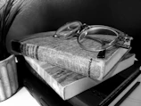 An artistic shot of vintage-inspired reading glasses beside a stack of classic novels.