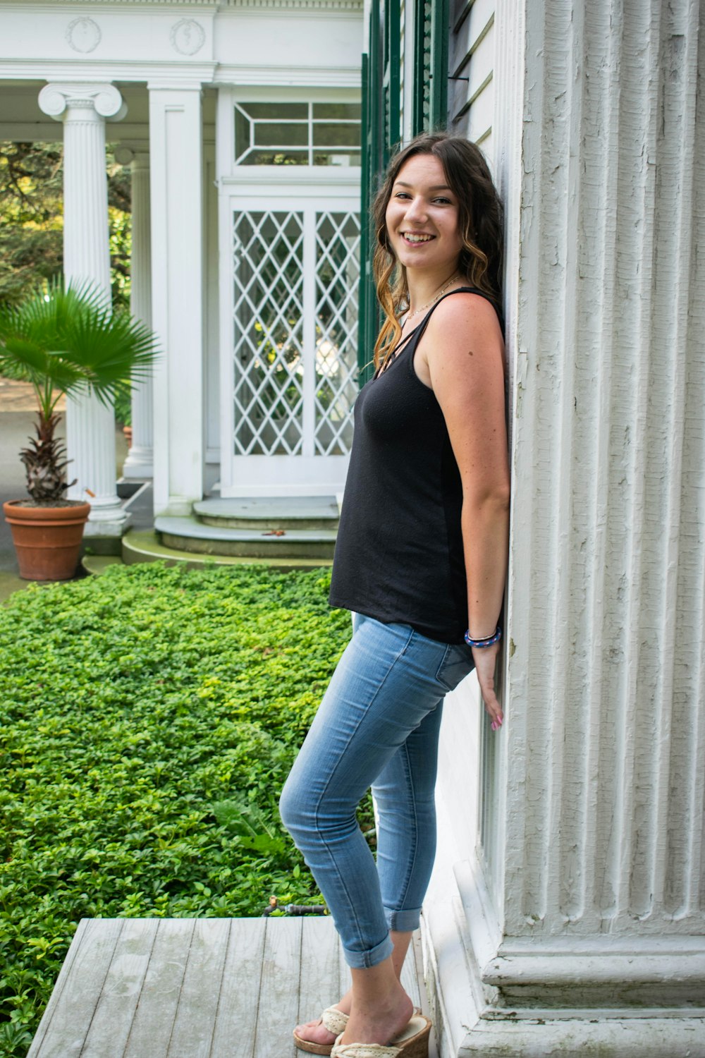 woman in black tank top and blue denim jeans standing on green grass field during daytime
