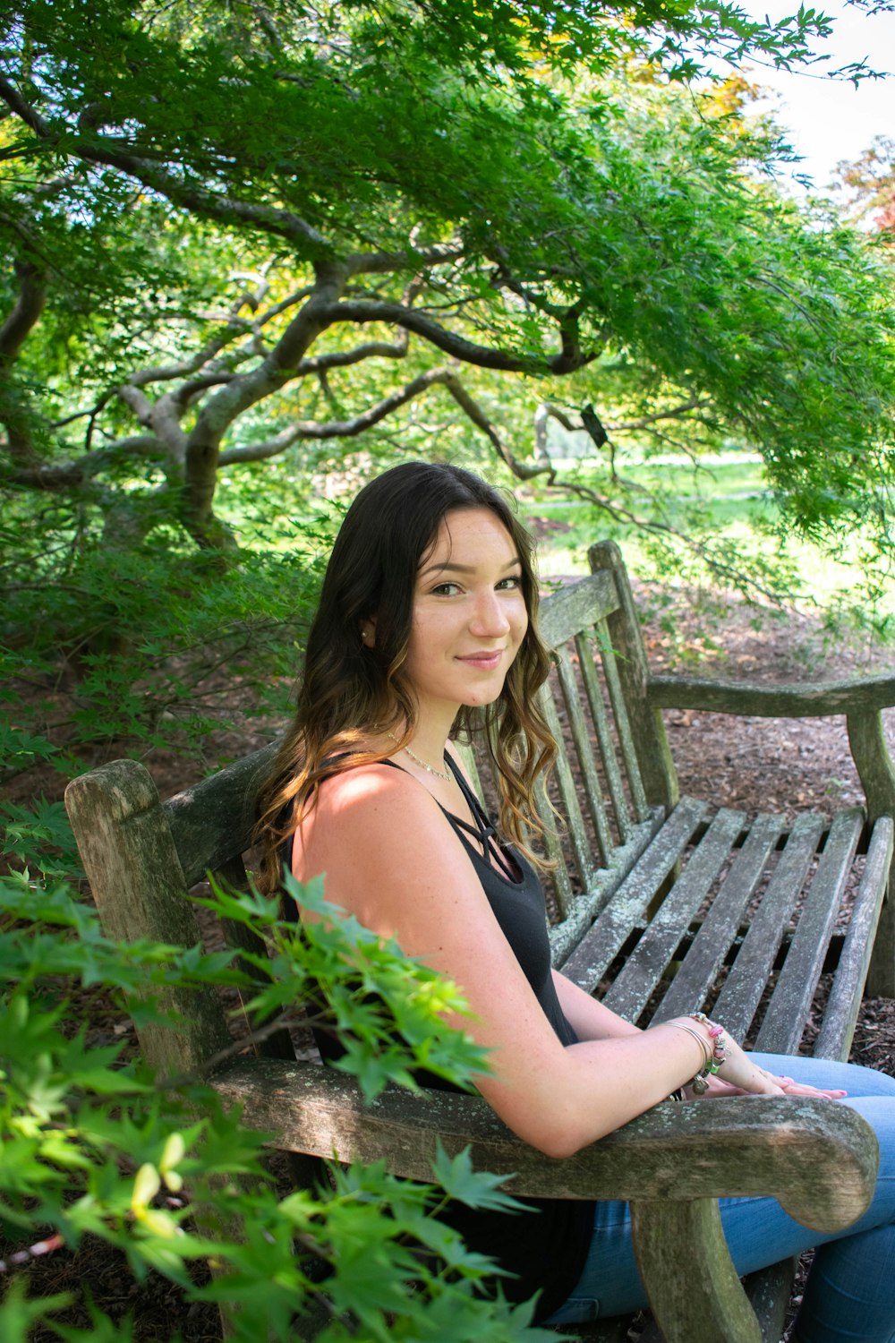 a woman sitting on a wooden bench in a park