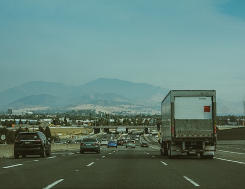 A busy highway scene where a mobile repair truck is servicing a broken-down truck off the side.