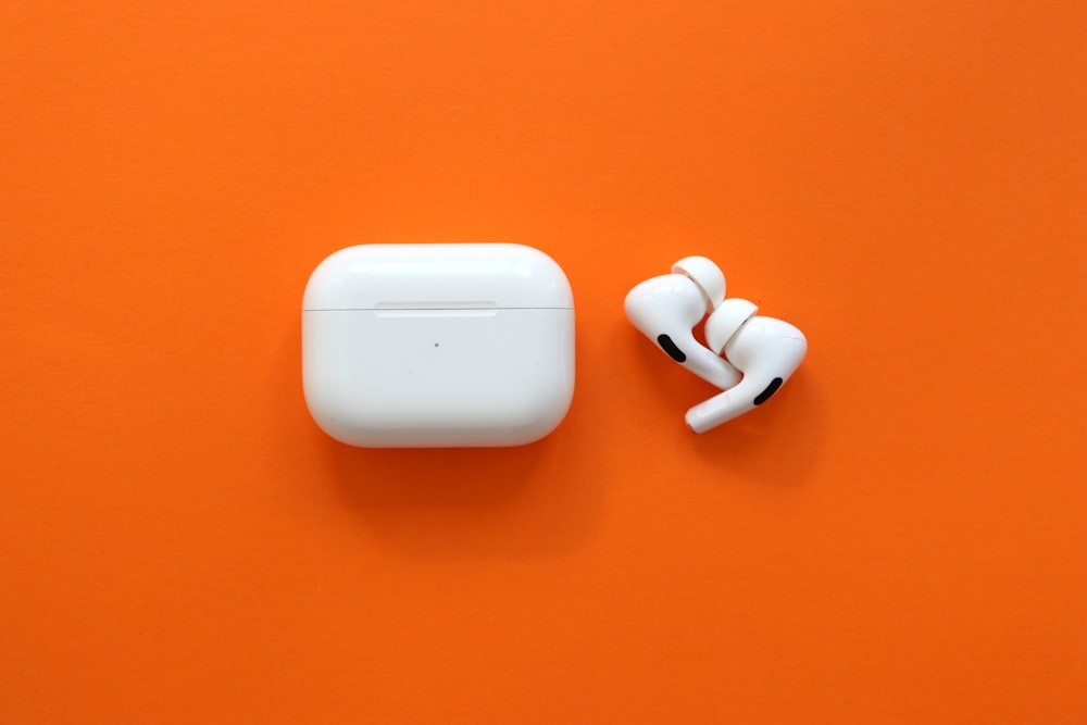 white apple airpods on orange surface