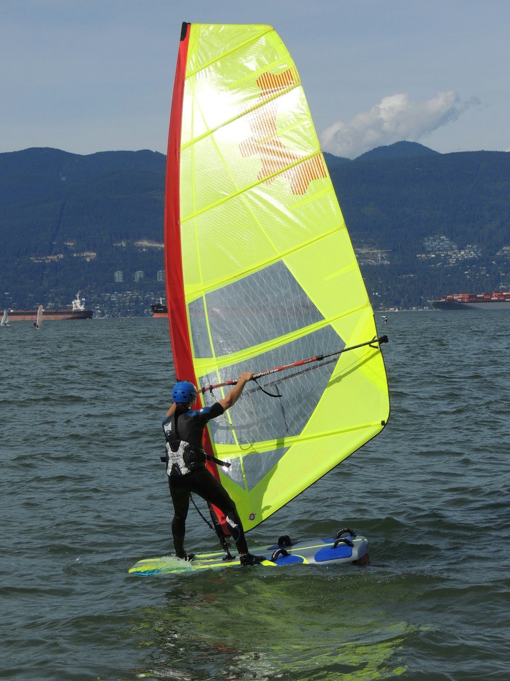 person in black wet suit riding on green and yellow sail boat during daytime