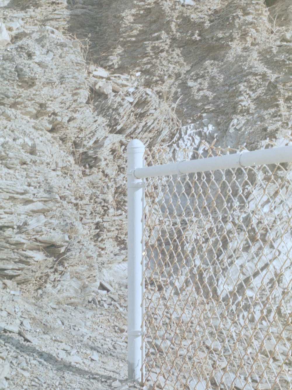 white metal fence near rocky mountain during daytime