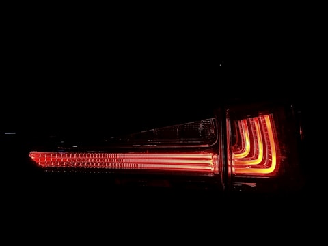 Bright red LED car taillight glowing in the dark, showcasing modern design elements with parallel lines and vertical sections.