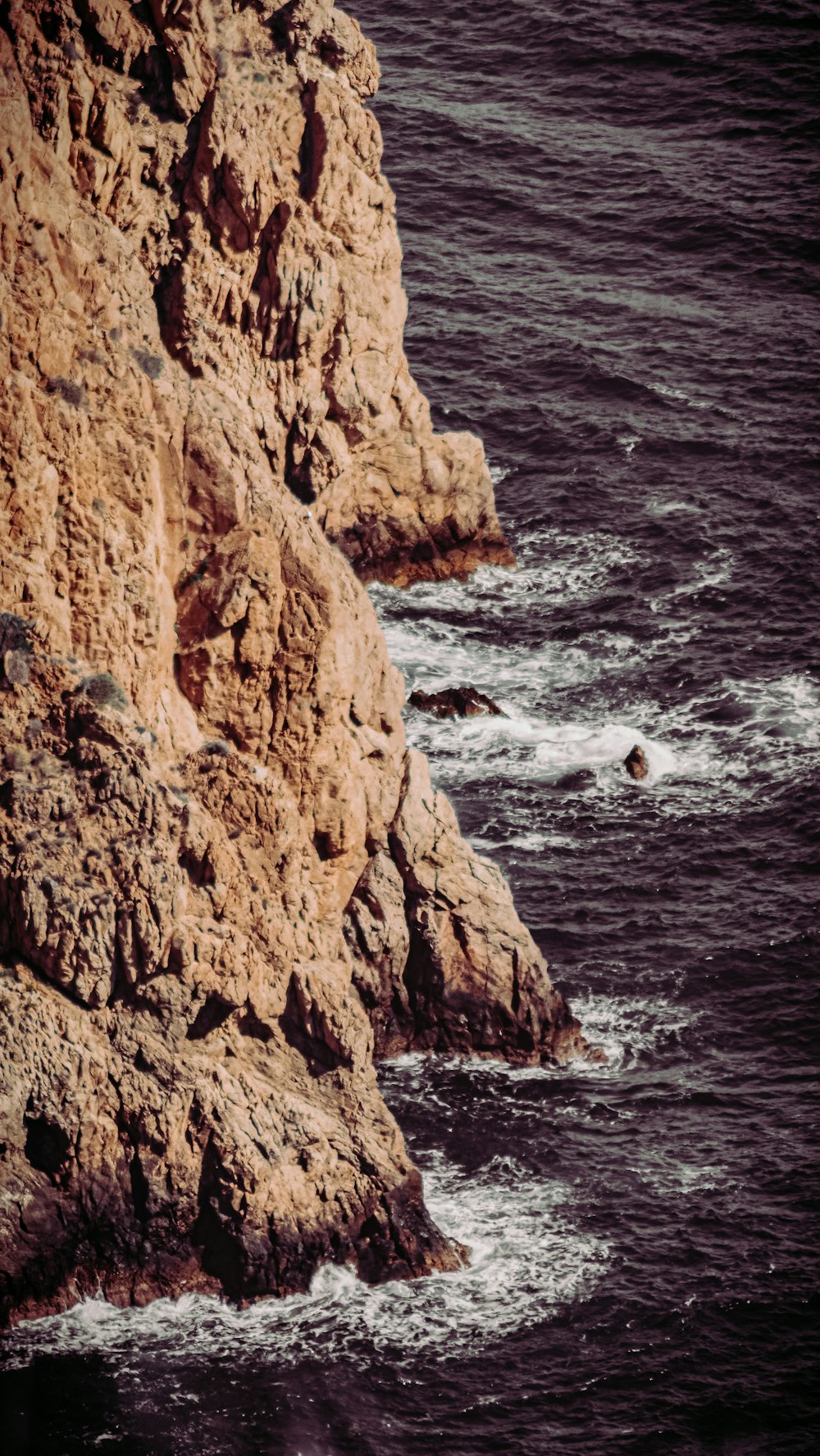 brown rock formation beside body of water during daytime