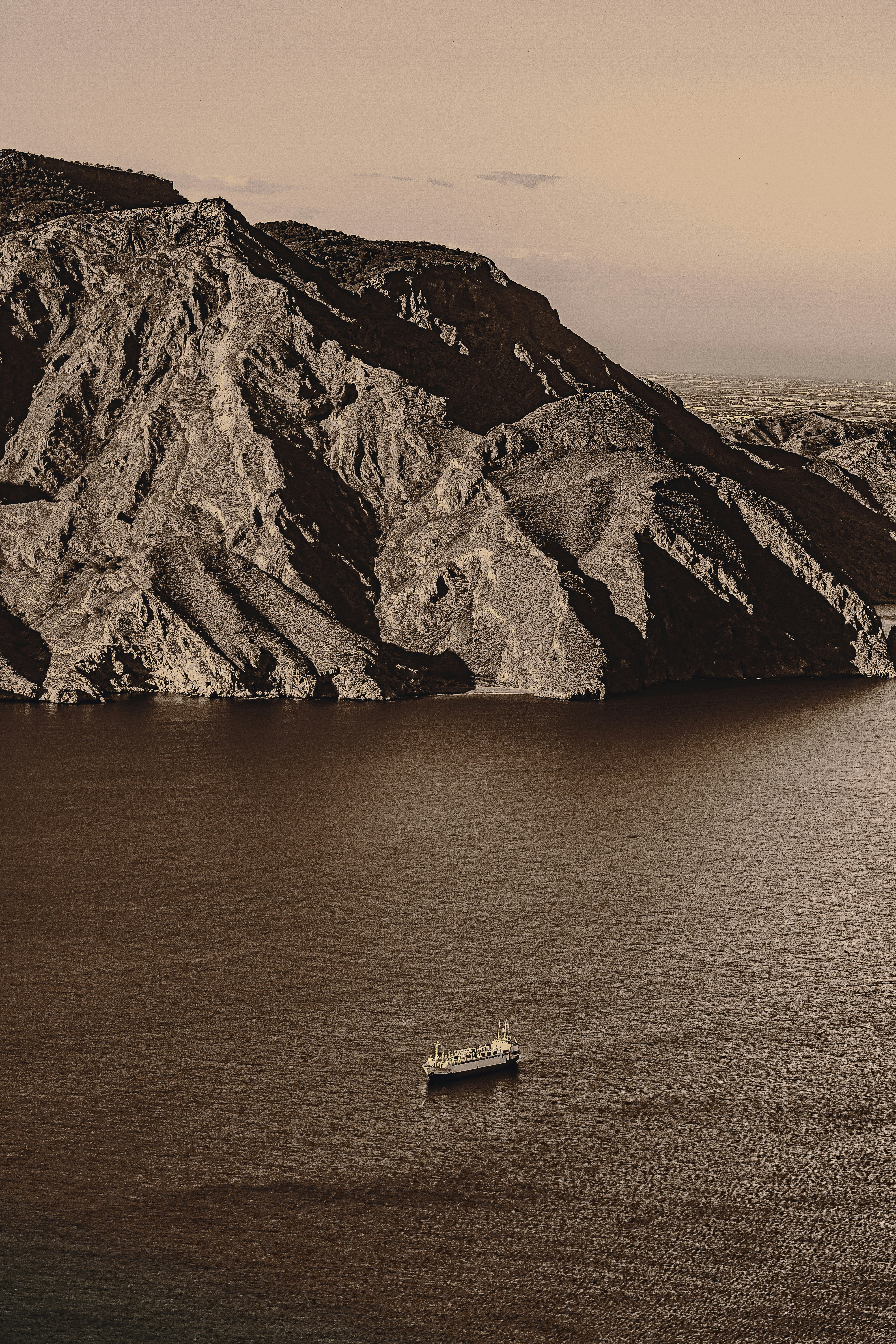 White and brown boat on body of water near brown rocky mountain during ...