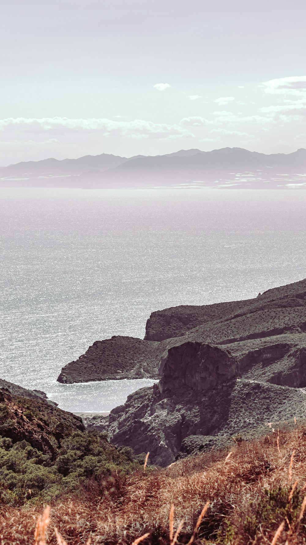 brown and green mountain beside body of water during daytime