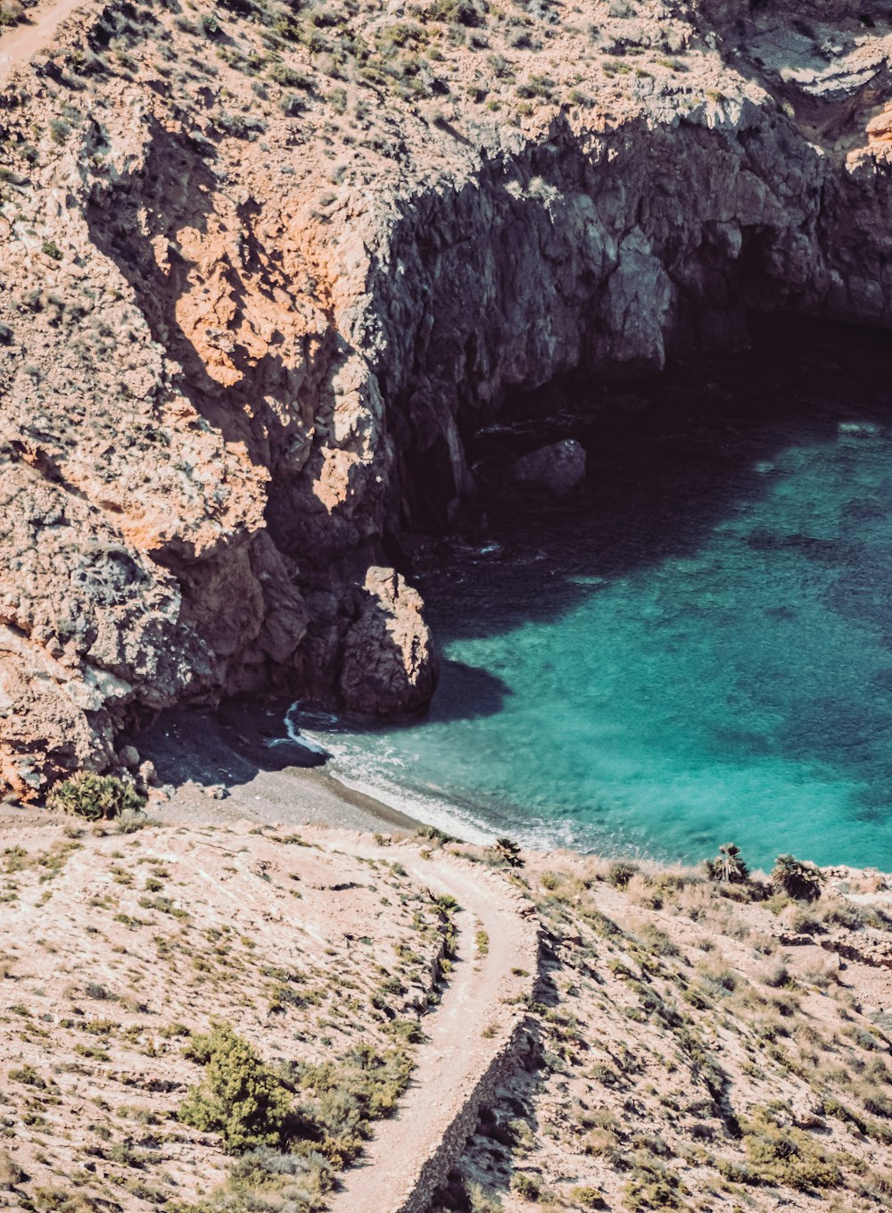 Montaña rocosa marrón junto al mar azul durante el día