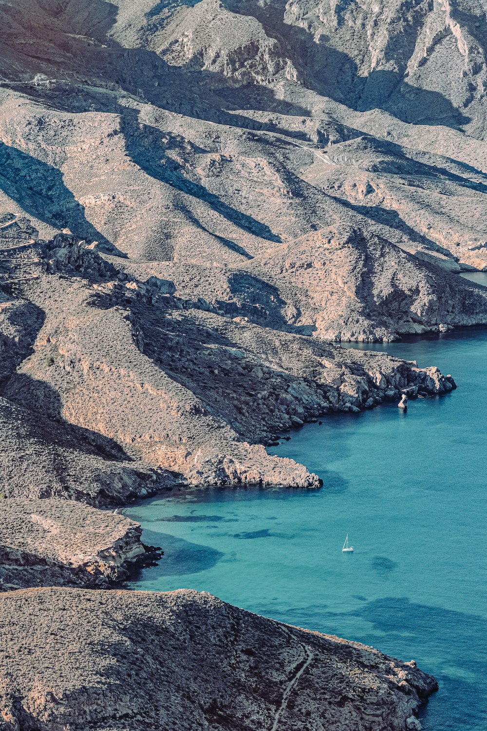 Vista aérea de las montañas marrones y verdes junto al mar azul durante el día