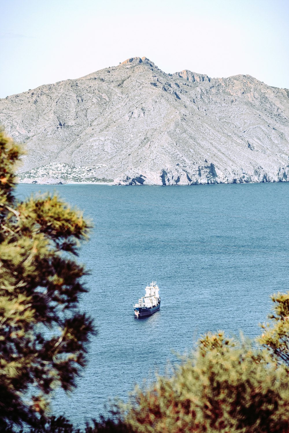 white boat on sea near mountain during daytime