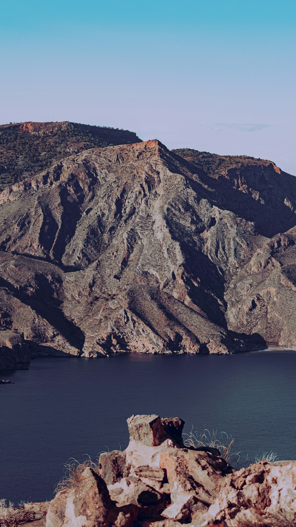 brown and green mountain beside body of water during daytime