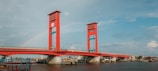 red bridge over river under blue sky during daytime