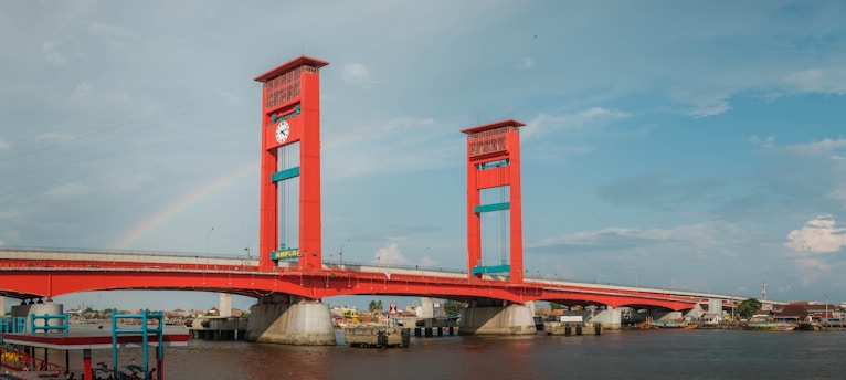 red bridge over river under blue sky during daytime