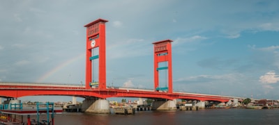 red bridge over river under blue sky during daytime