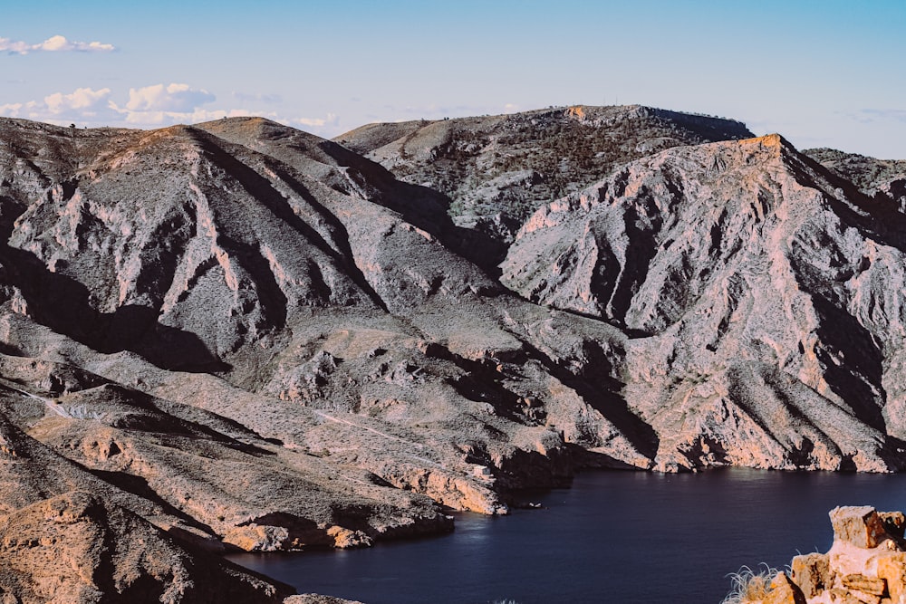 brown and green mountain beside body of water during daytime