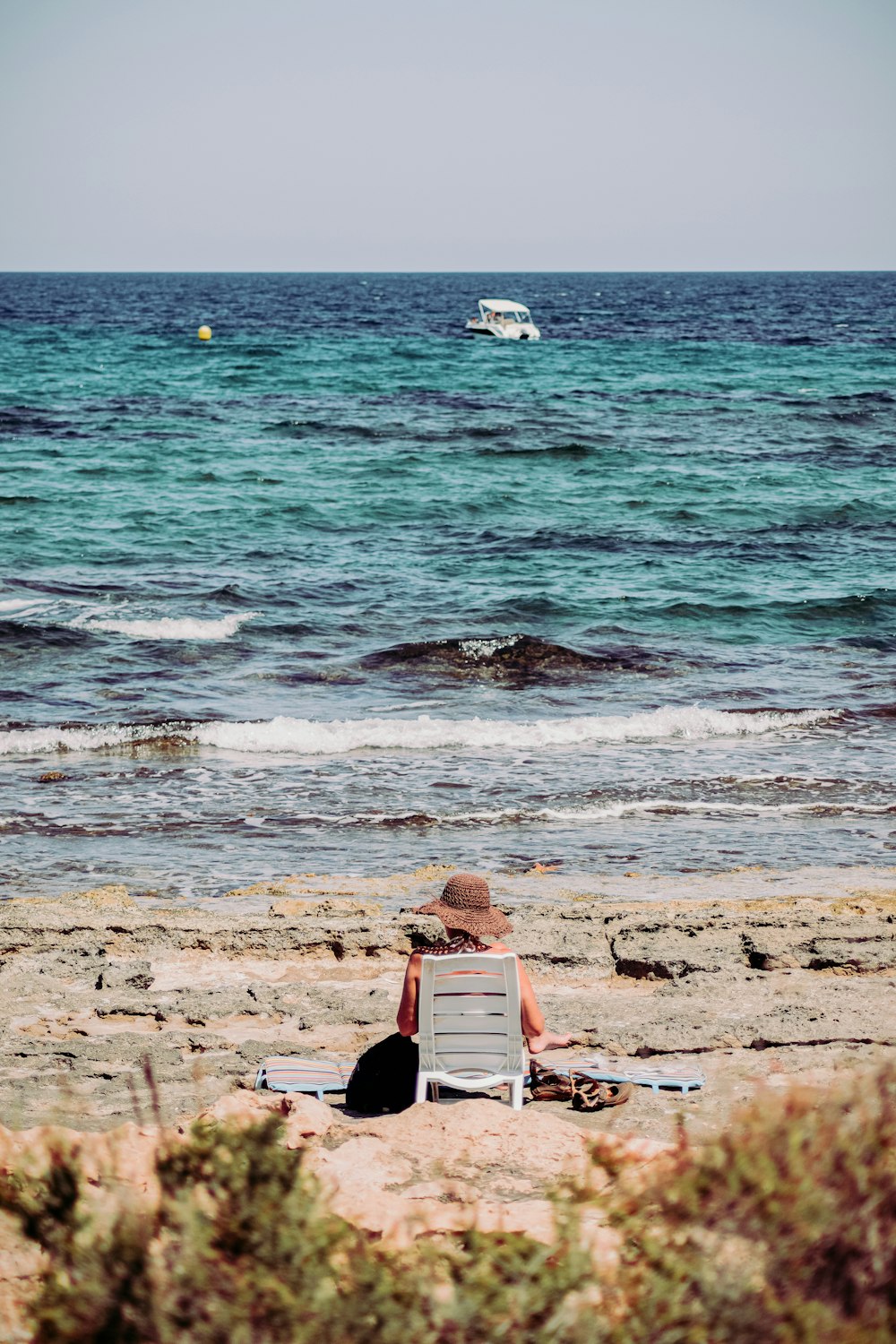 man in black shirt sitting on red and white surfboard on seashore during daytime