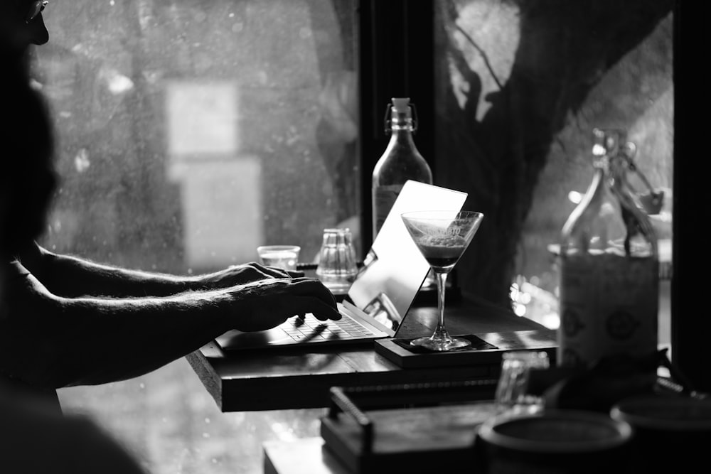 grayscale photo of person holding pen and paper