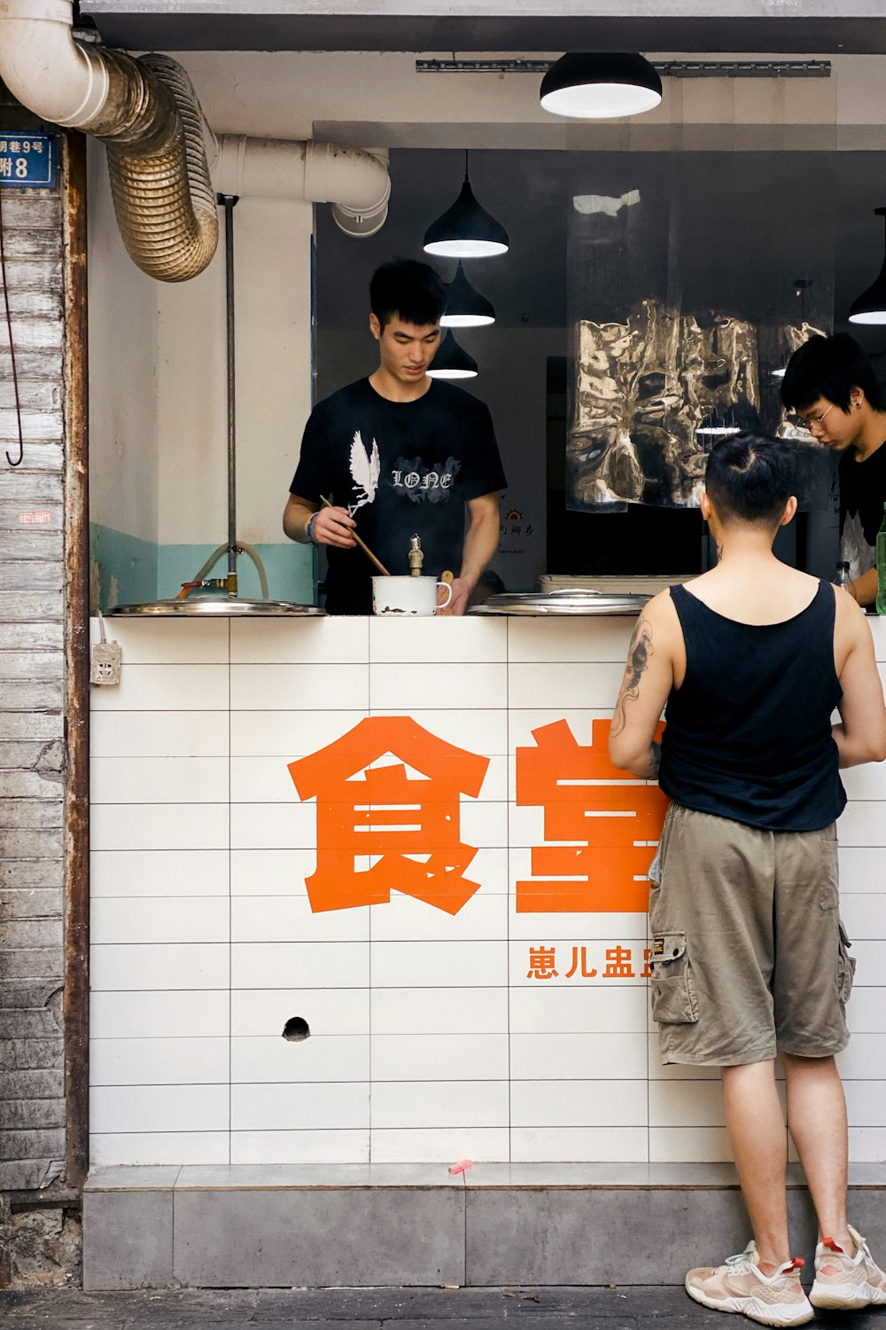 man in black tank top standing beside glass wall