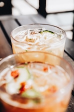 clear drinking glass with ice cubes and sliced of tomato