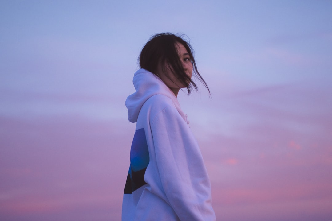 woman in white hoodie standing under gray sky during daytime