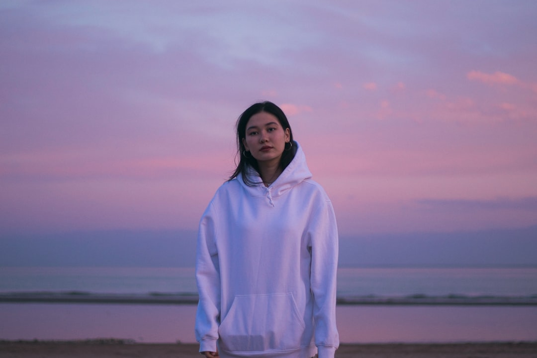 woman in white hoodie standing on beach during daytime