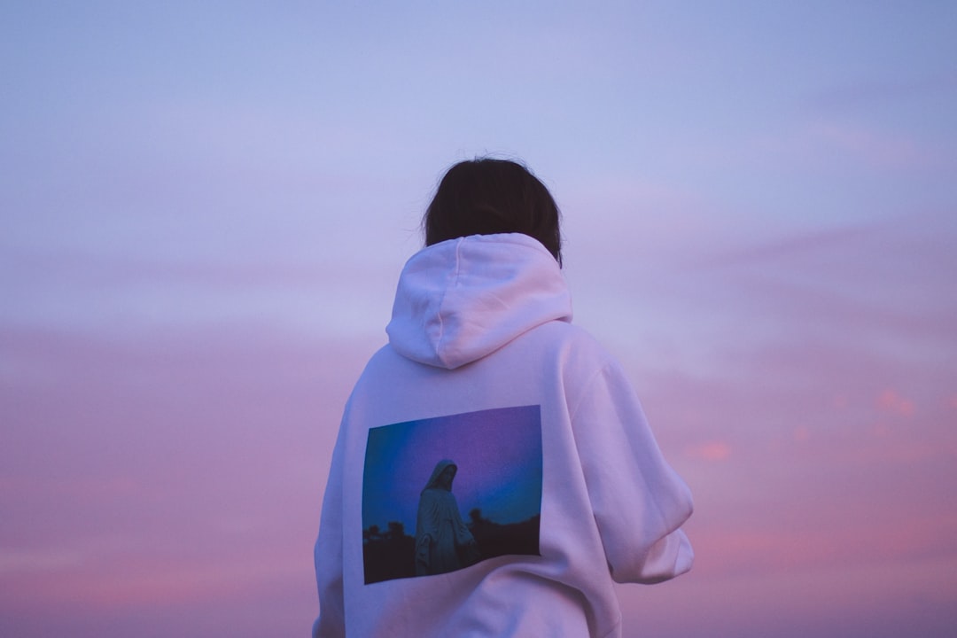 person in white hoodie standing on brown field during daytime