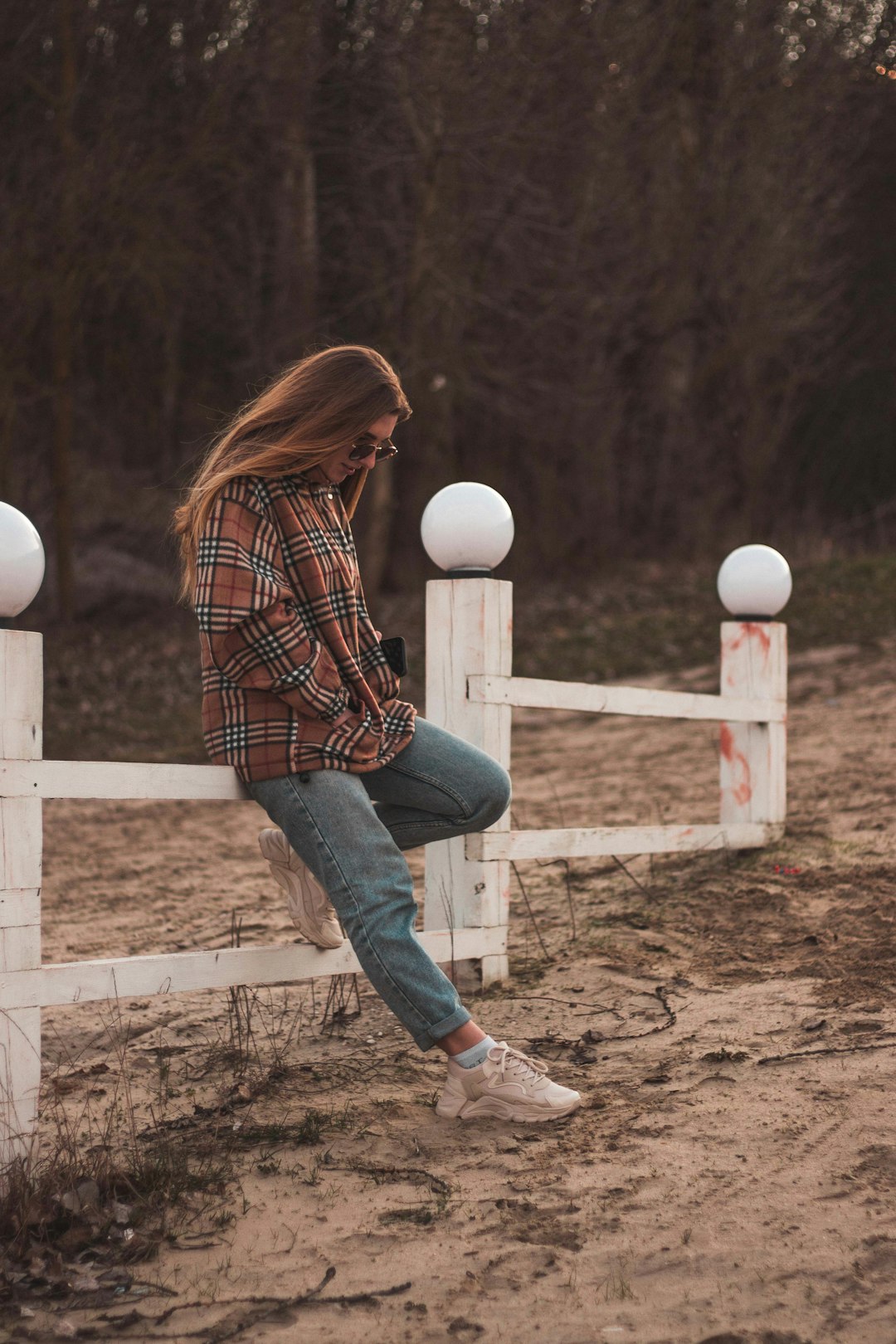 woman in red and white plaid dress shirt and blue denim jeans sitting on white wooden