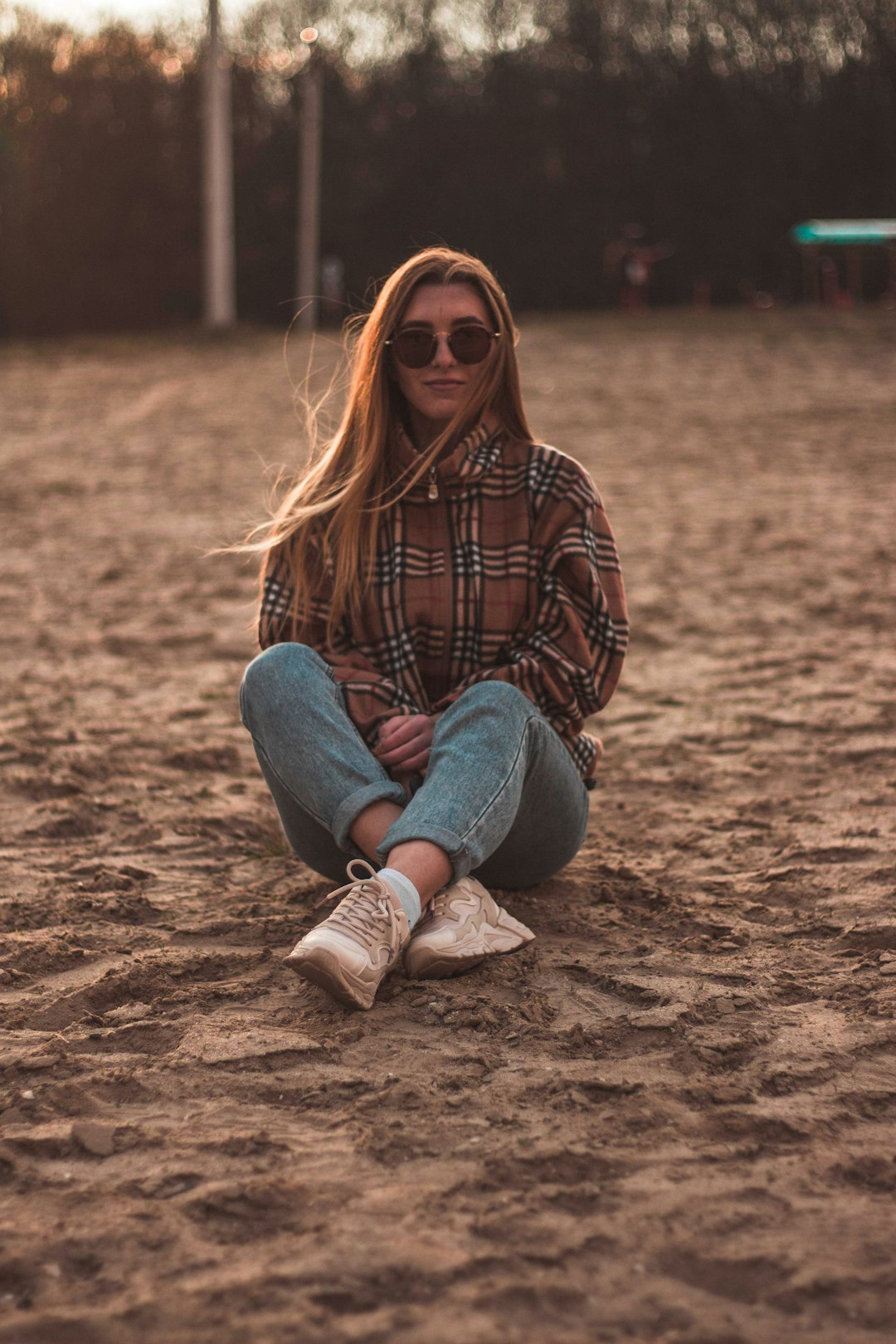 woman in black and white plaid long sleeve shirt and blue denim jeans sitting on brown